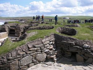 Visitors examining the remains of another sophisticated Neolithic structure in Orkney - Scara Brae.